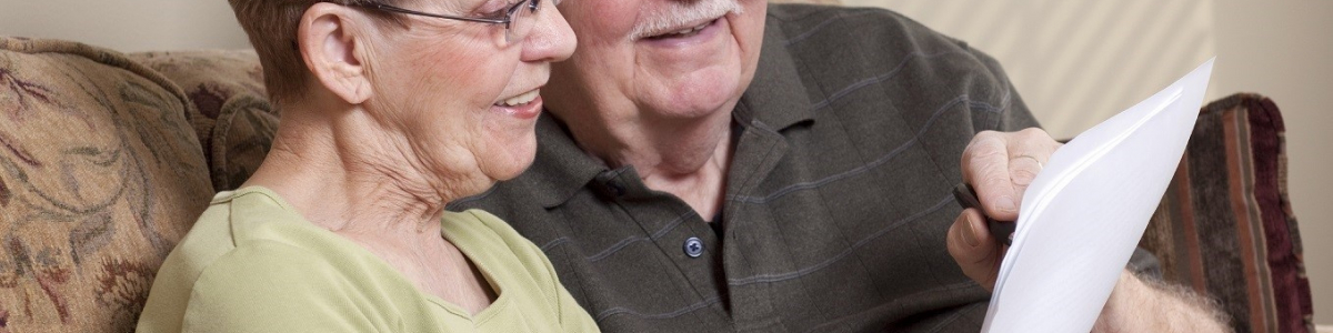 Two older people smiling and sitting with a document